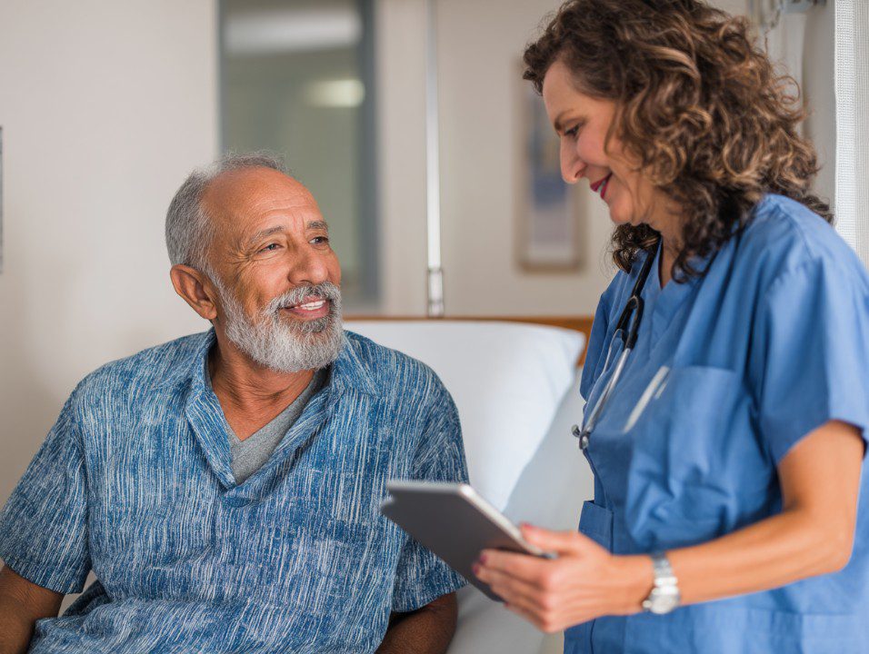 Senior man smiling warmly at a healthcare professional during a routine checkup, symbolizing trust and compassionate medical care.