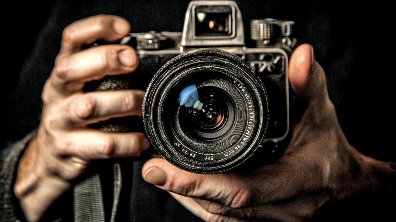 Cinematic close-up shot of hands firmly gripping a vintage camera, emphasizing the lens and manual controls.