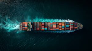 Cinematic top-down view of a container cargo ship moving through the ocean, loaded with multicolored shipping containers.