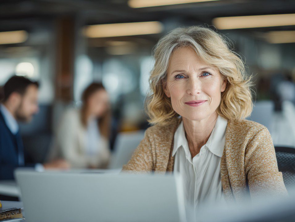 A professional female insurance agent smiles at the camera in a modern office, ideal for business and insurance content.