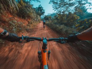 A man riding a mountain bicycle on a dirt trail, surrounded by greenery, showcasing the thrill of outdoor cycling.