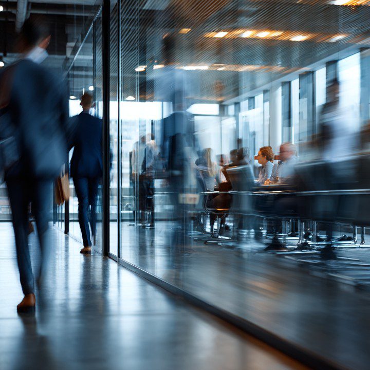 Business professionals having a meeting in a glass-walled conference room, reflecting modern corporate culture and teamwork.