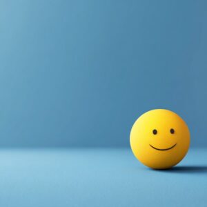 A single yellow happy emoji ball sits on the right side of a minimalist blue background, symbolizing positivity and digital emotion.