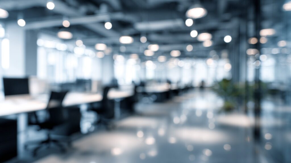 A blurred image of a spacious open office with modern furnishings in blue-grey tones, ideal for business presentation backdrops.