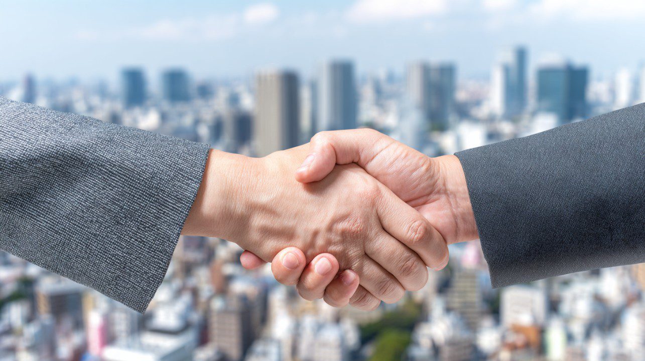 Close-up of a handshake between two business professionals with a modern city skyline blurred in the background.