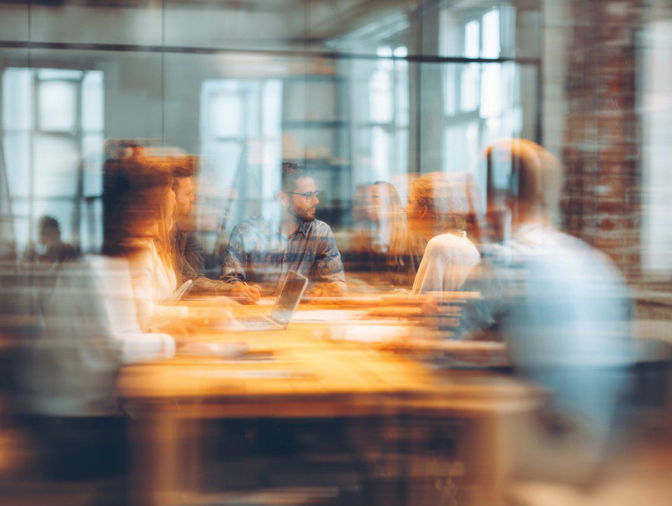 Modern business team meeting with motion blur effect in a bright office, symbolizing active collaboration and dynamic teamwork.
