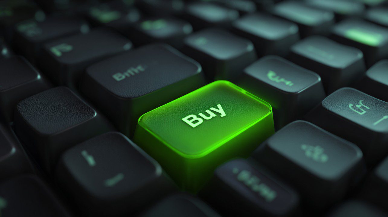 Macro close-up of a glowing green "Buy" key on a black computer keyboard symbolizing digital purchasing and e-commerce.