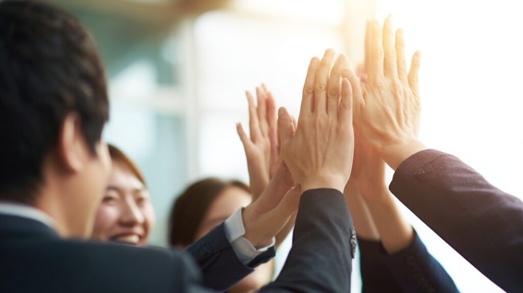 Close-up of Korean office workers joyfully giving a group high-five in a bright office.