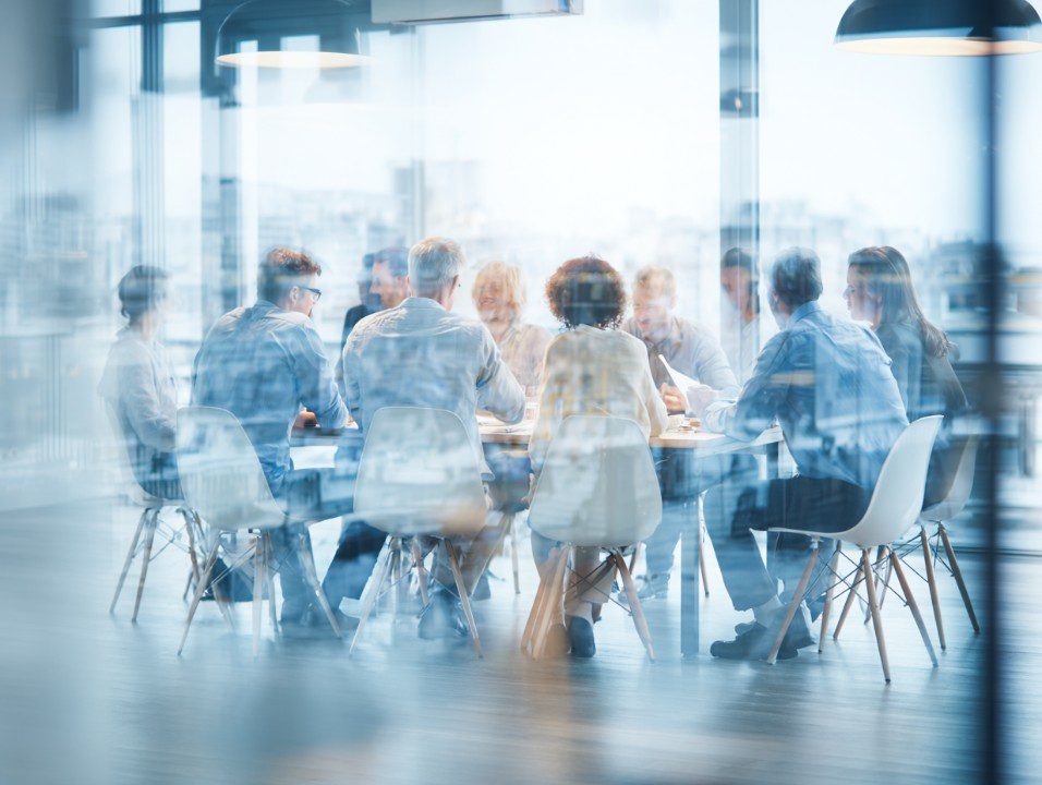 Modern business team having a meeting in a bright office with glass walls, showing collaboration and teamwork.