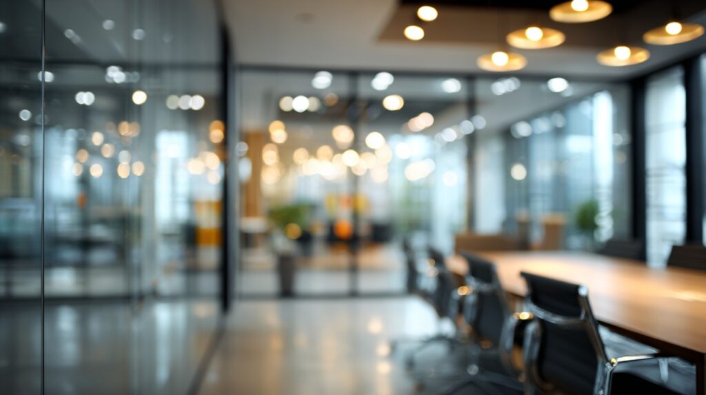 Blurred modern office interior with glass walls and conference table, perfect for professional business and corporate use.