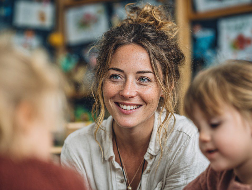 A speech therapist with a friendly smile working closely with children during a therapy session.