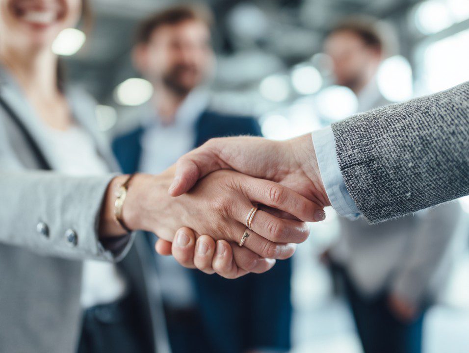 Close-up of two professionals shaking hands in a modern office.