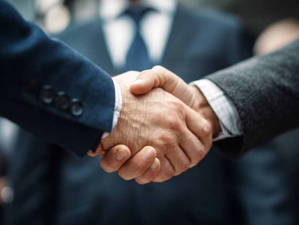 Close-up of two businesspeople shaking hands in a professional setting.