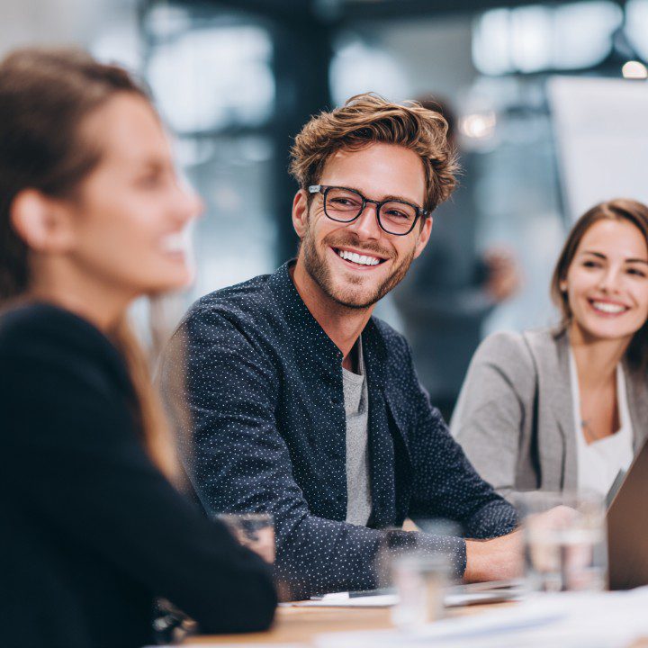 Smiling man in glasses participating in a modern business meeting with colleagues.