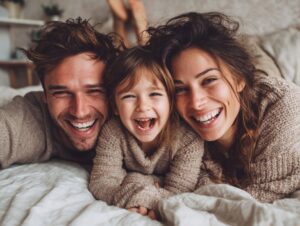 Smiling parents and child lying in bed together, enjoying a joyful morning.