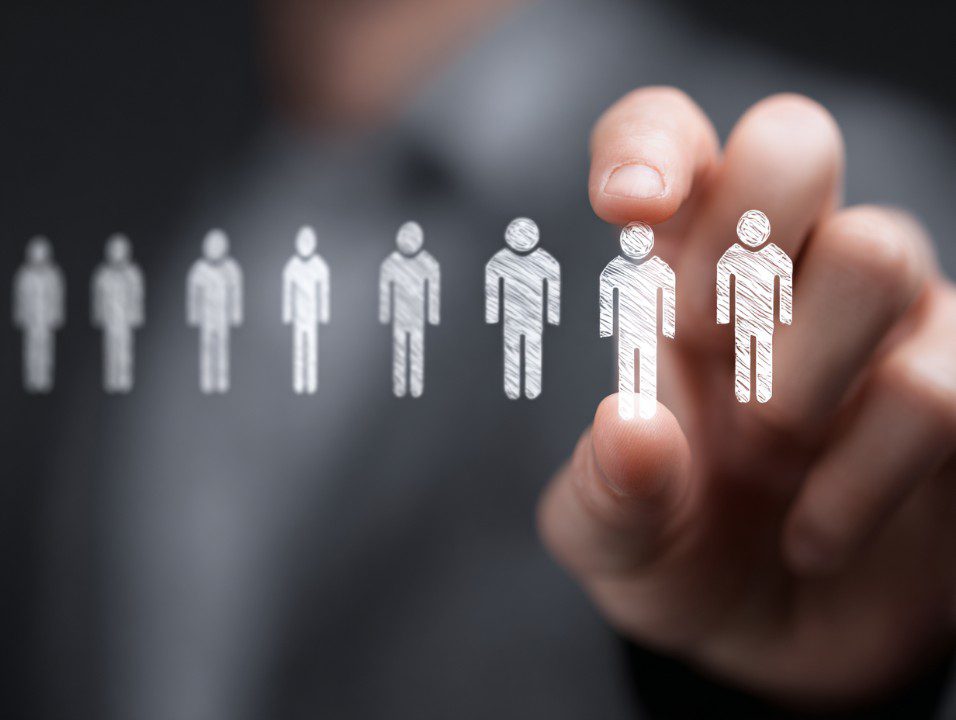 Business person’s hand selecting a sketched human icon representing recruitment and HR.