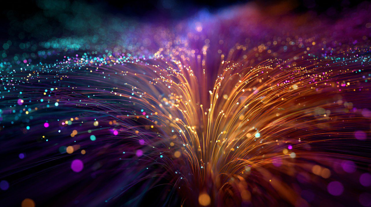 Vibrant 3D image of multicolored fiber optic strands bursting outward, symbolizing neural networks or data flow in technology.