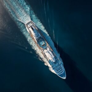 Aerial image of a large white cruise ship sailing through deep blue ocean water, showcasing luxury and travel ambiance.