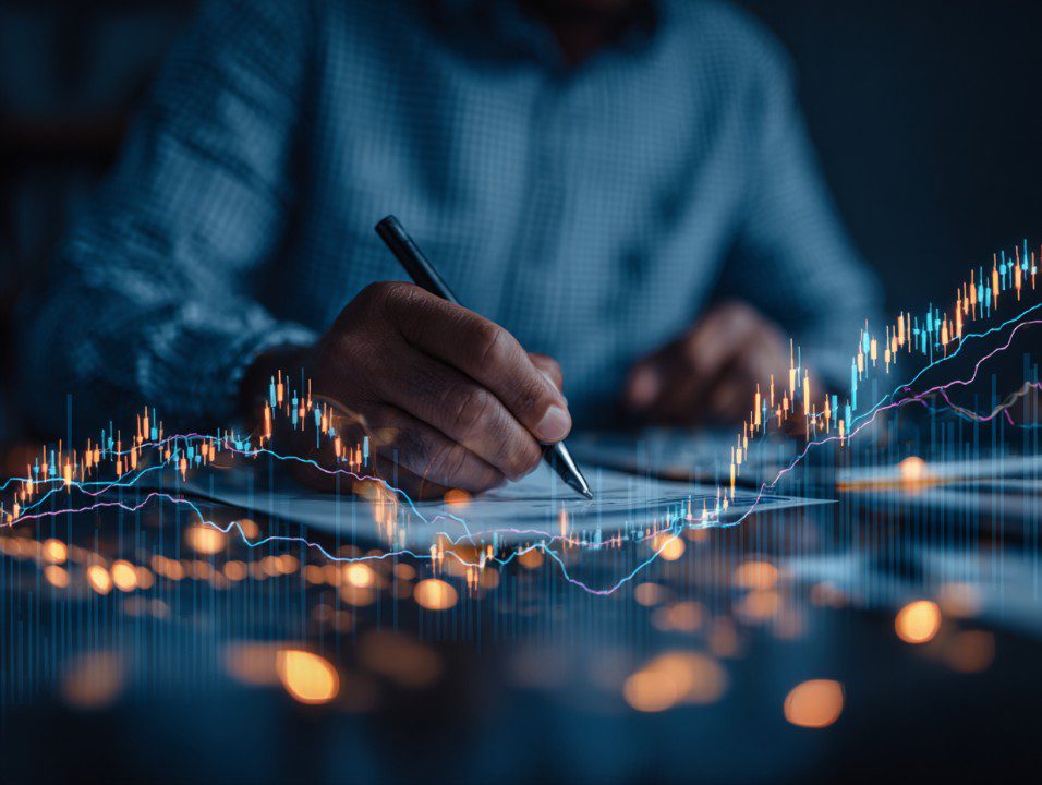 Businessman analyzing forex trading graph and financial charts at a desk, representing investment decisions and market strategy.