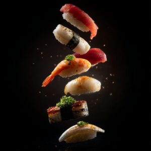 Assorted sushi pieces floating vertically in mid-air on a black background, styled as a dramatic food art composition.