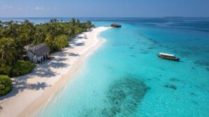 Aerial view of a tropical island with white sand beach, turquoise sea, palm trees, and a boat in clear shallow water.