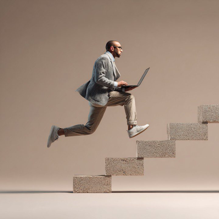 Professional businessman leaping up concrete stairs while working on a laptop, representing ambition and career progress.