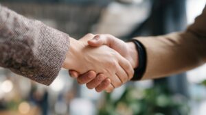Close-up of two people shaking hands in a professional setting, symbolizing partnership, trust, and successful business collaboration.