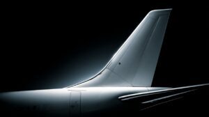 Studio-lit side view of a modern airplane’s vertical tail fin, symbolizing aviation design, precision, and aerospace technology.