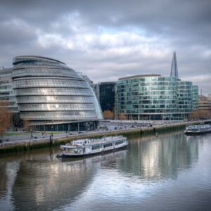 View of More London Riverside with City Hall and The Shard behind, boats on the River Thames, and cloudy sky in London.