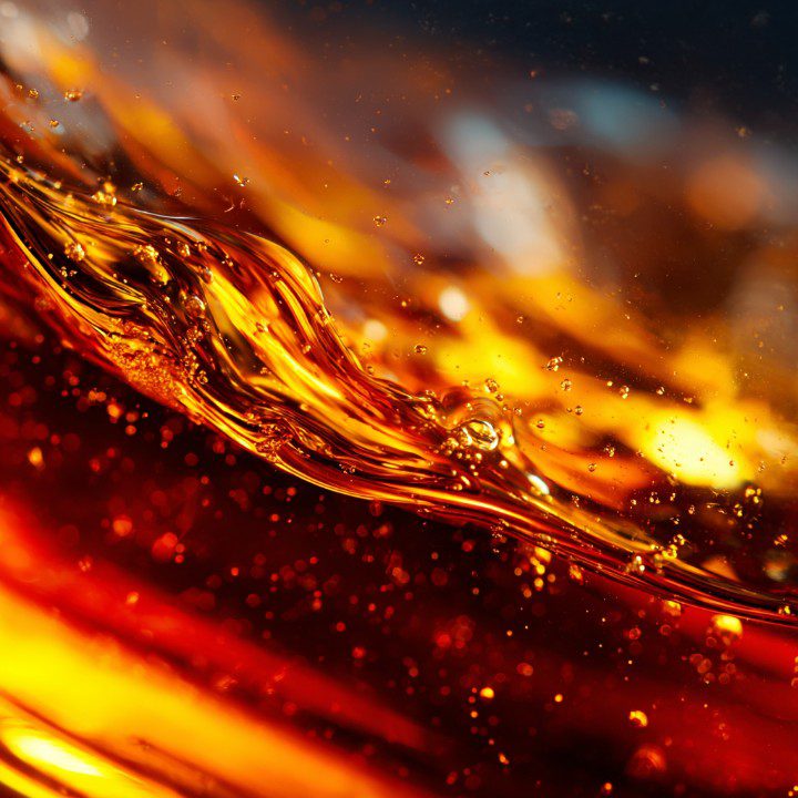 Macro shot of swirling golden whisky or cognac liquid in motion, capturing rich amber tones and smooth textures for luxury visuals.